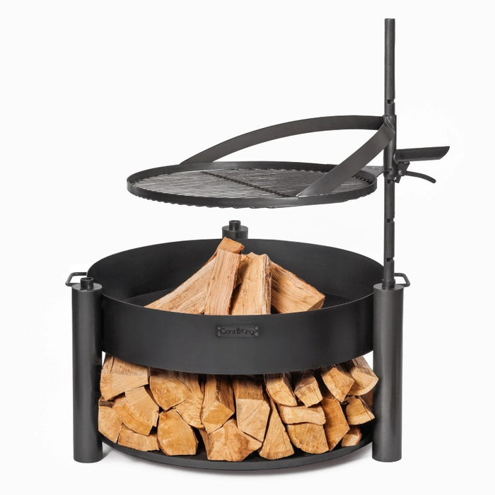 Eldfat MONTANA X med ved i eldfatet och grillgaller i upphöjt läge, redo att användas.