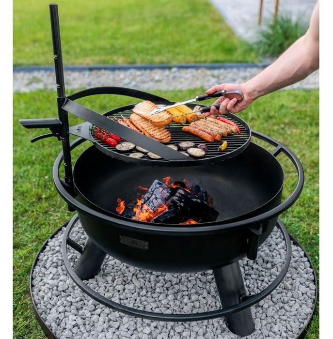 Man lagar mat på grillplatta över elden i Bandito eldfat från Cook King.