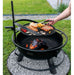 Man lagar mat på grillplatta över elden i Bandito eldfat från Cook King.