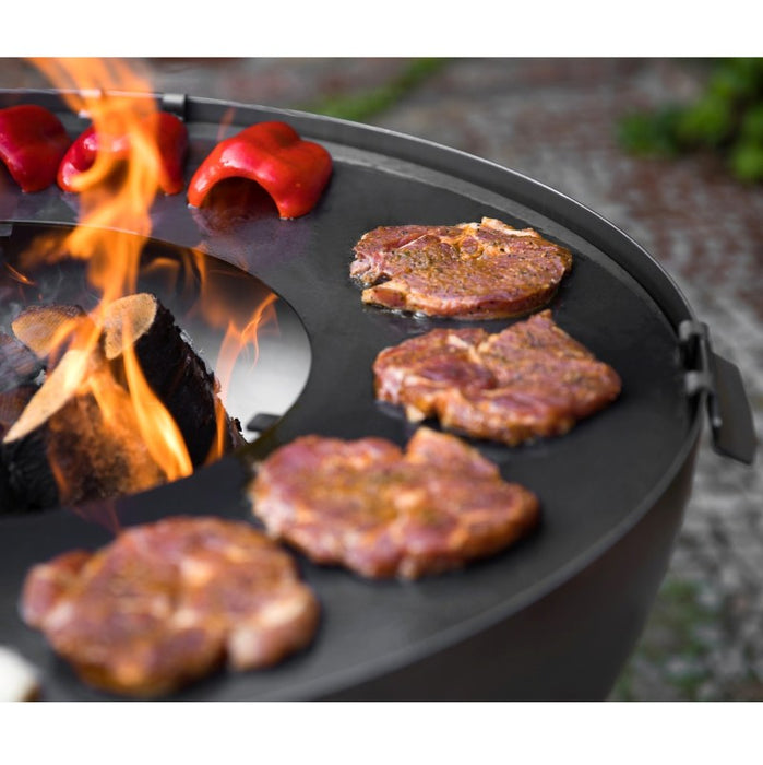 Närbild på grillplatta där köttbitar och paprikor grillas över öppen eld.